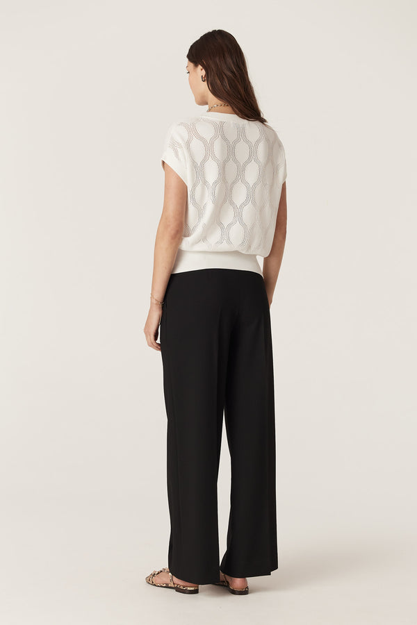 Model wearing a white Silk Tencel Wave Knit Top with pointelle jersey stitch and black pants.