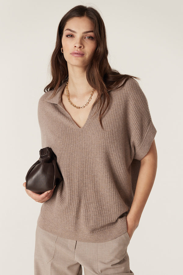 Woman in a mocha Cashwool waffle knit V-neck top with collar, holding a dark brown clutch.