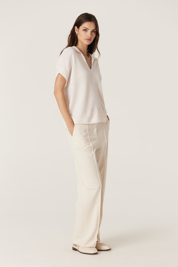 Woman in a milk-colored Cashwool waffle knit V-neck top with collar and cream wide-leg pants.