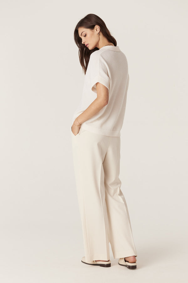 Woman in a relaxed fit milk-colored Cashwool waffle knit V-neck top and cream wide-leg pants.