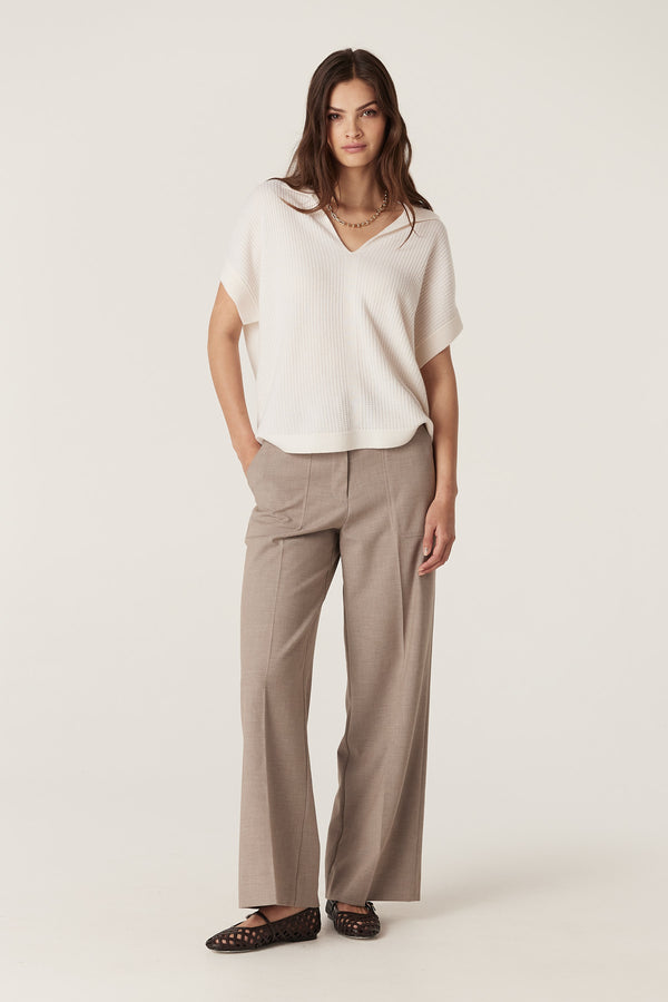 Woman in a relaxed fit milk-colored Cashwool waffle knit top with a V-neck collar and brown trousers.