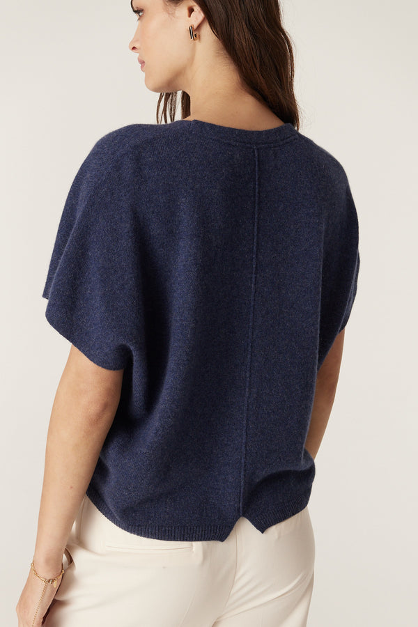 Woman wearing a relaxed fit denim blue cashmere top with a V-neck and center back seam detail.