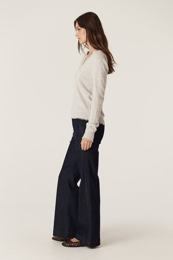 Model wears a Frost Cashwool Aura Jumper with V-neck and loop fringing, paired with dark jeans.
