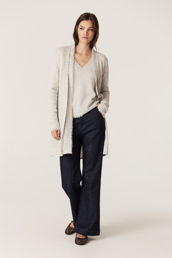 Model wears a Frost Cashwool Aura Cardigan with fringing, over a matching top and dark jeans.