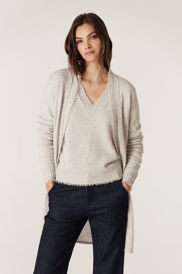 Woman in a frost Cashwool Aura cardigan with fringing, worn over a matching V-neck top and dark jeans.