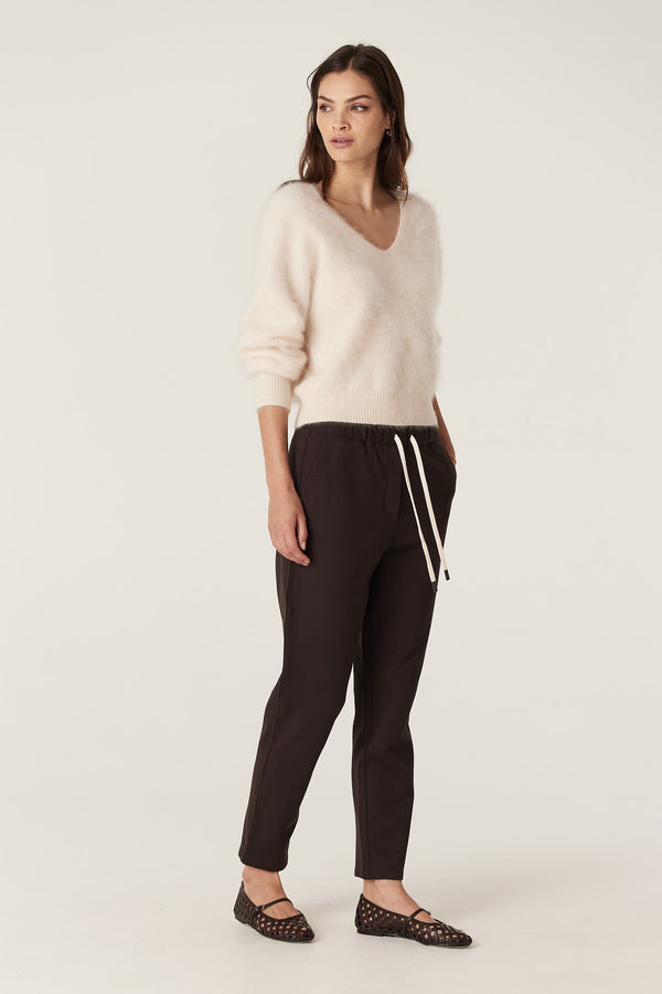 Model wears a parchment brushed cashwool V-neck jumper with dark trousers and black woven flats.
