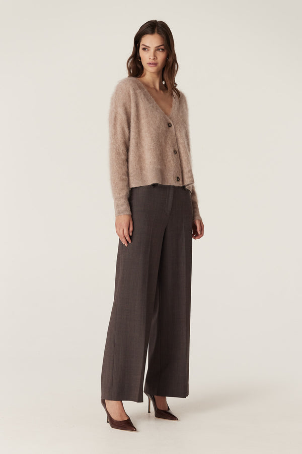 Woman wearing a relaxed fit mink brushed cashwool V-neck cardigan with button front and dark wide-leg trousers.
