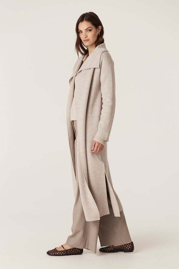 Woman in a longline mushroom Parsons Merino Cardigan with side splits, paired with matching knit top and pants.