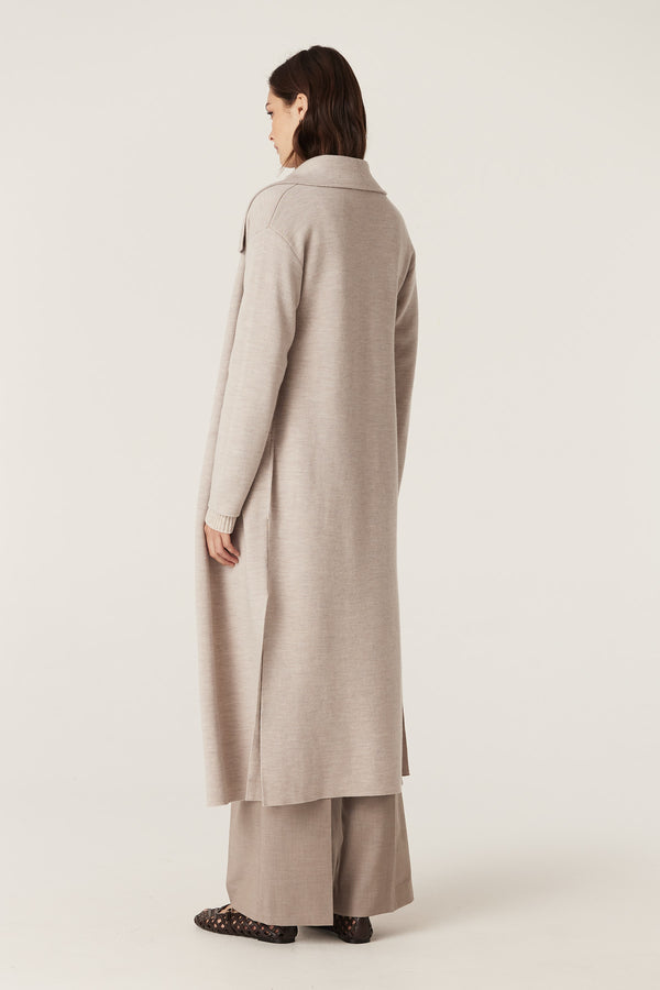 Woman wearing a longline mushroom Parsons Merino Cardigan with side splits and pockets, shown from the back.
