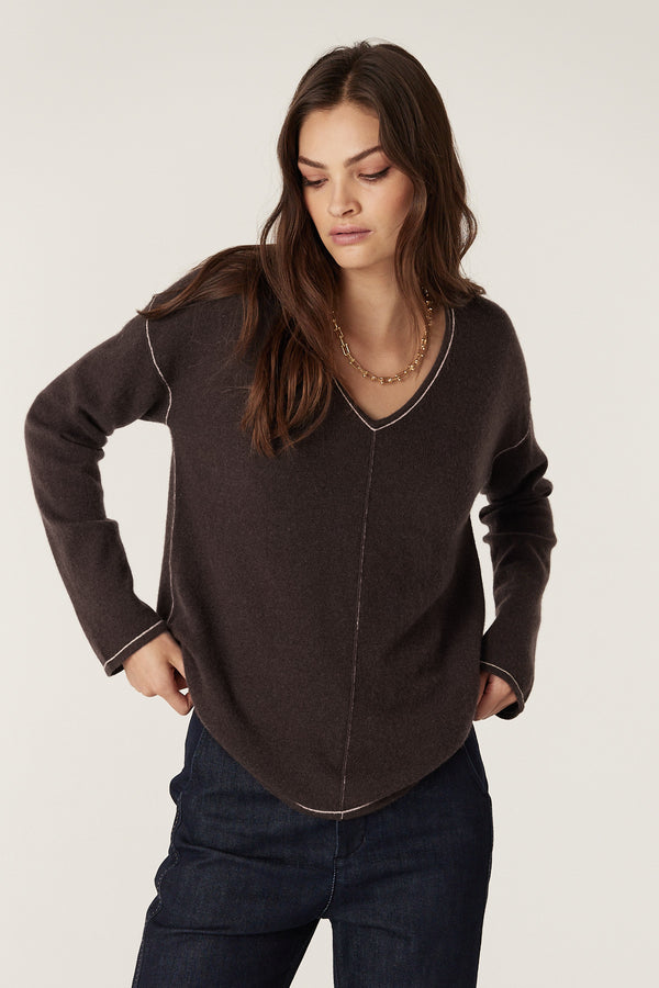 Model wears a chocolate pure cashmere V-neck jumper with exposed seams and contrast stitching.