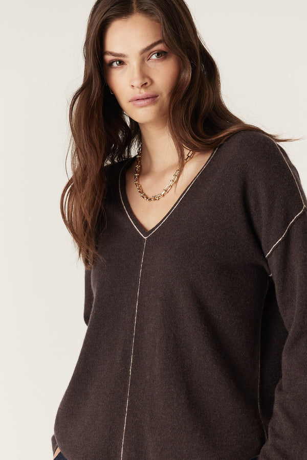 Chocolate pure cashmere V-neck jumper with exposed seams and contrast stitching, worn by a model.