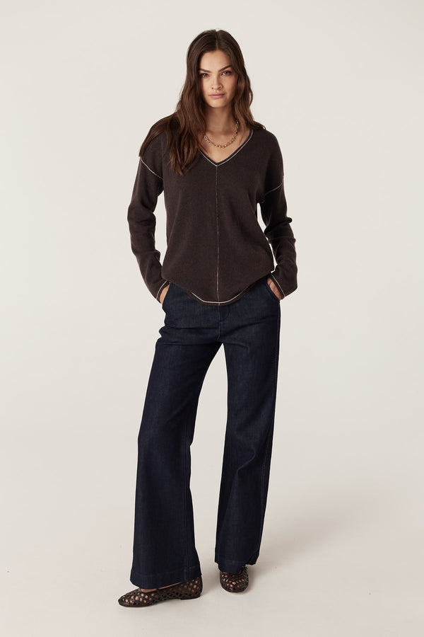 Chocolate pure cashmere V-neck jumper with exposed seams and contrast stitching, worn by a model.