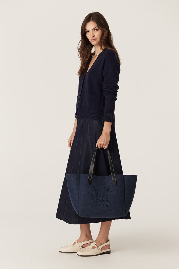 Navy Cashwool V-neck cardigan with pockets, worn by a woman with a denim skirt and tote bag.