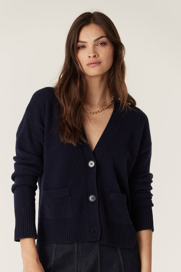 Navy Cashwool V-neck cardigan with front buttons, pockets, and ribbed cuffs on a woman.