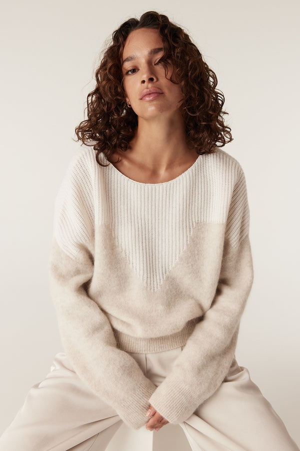 Woman in oatmeal boat neck knit jumper with ribbed yoke and drop shoulders.