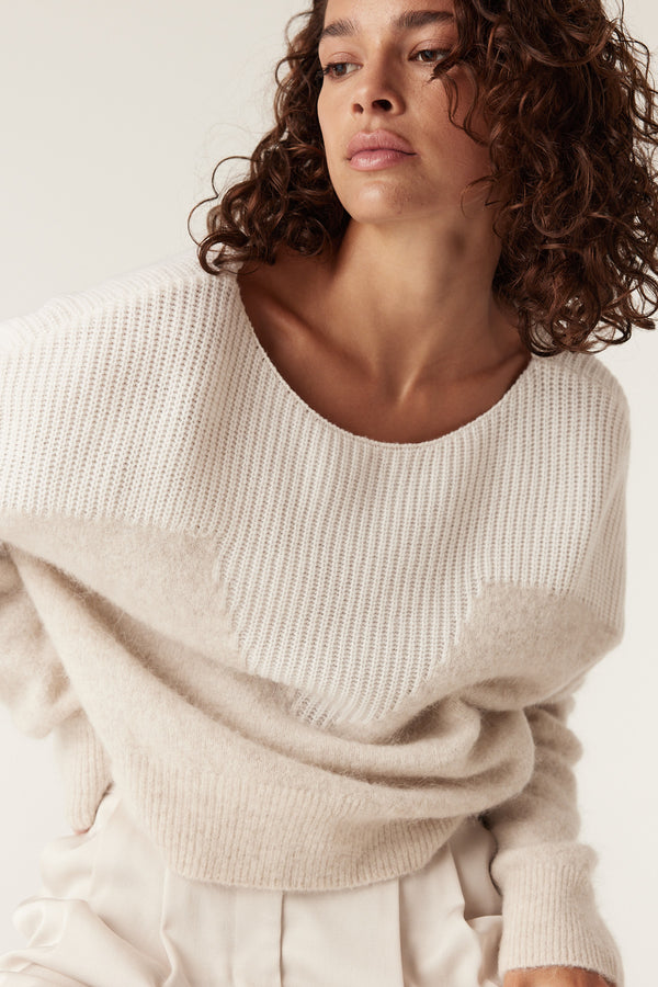 Woman wearing an oatmeal boat neck knit jumper with ribbed details and a relaxed fit.
