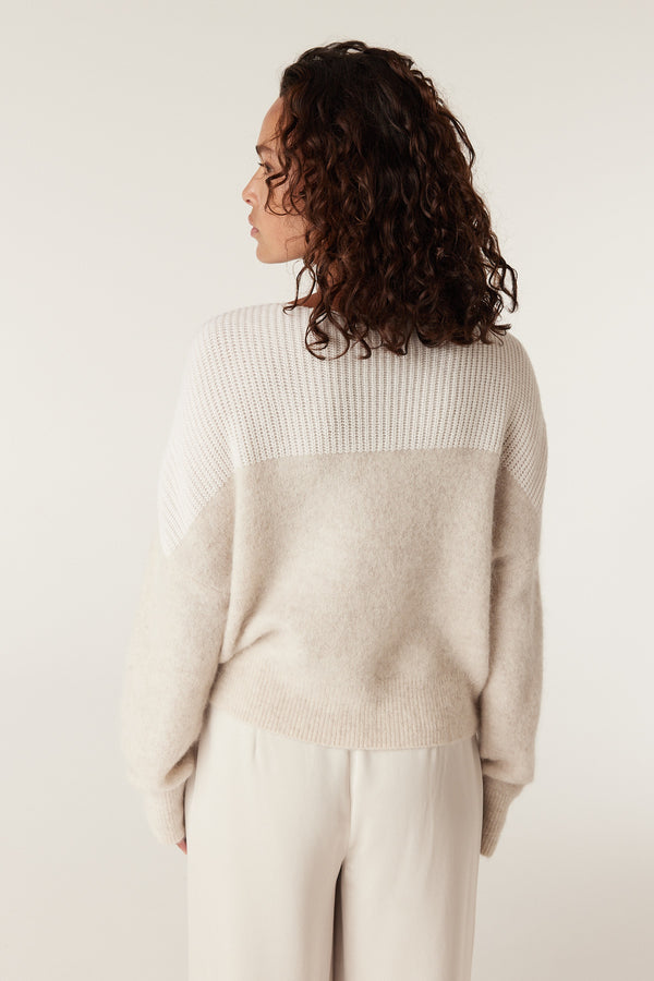 Woman in an oatmeal boat neck knit jumper with ribbed top and smooth body.