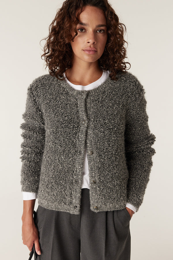Woman in an ash grey teddy knit cardigan with long sleeves and front buttons over a white tee.