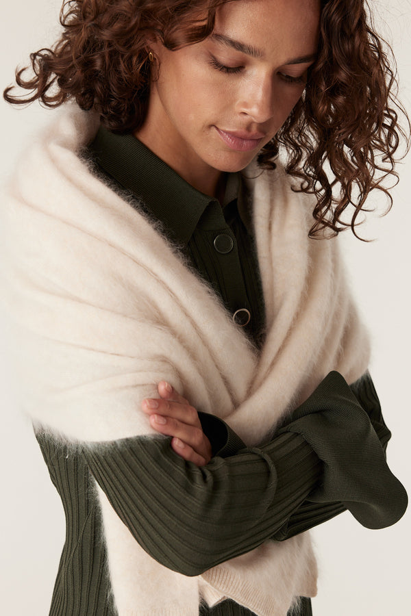 Brushed parchment cashwool button poncho draped over a dark green ribbed top.