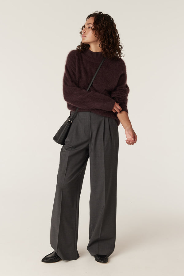 Woman wearing a cozy Shiraz brushed cashwool turtle neck jumper with dark grey wide-leg trousers.