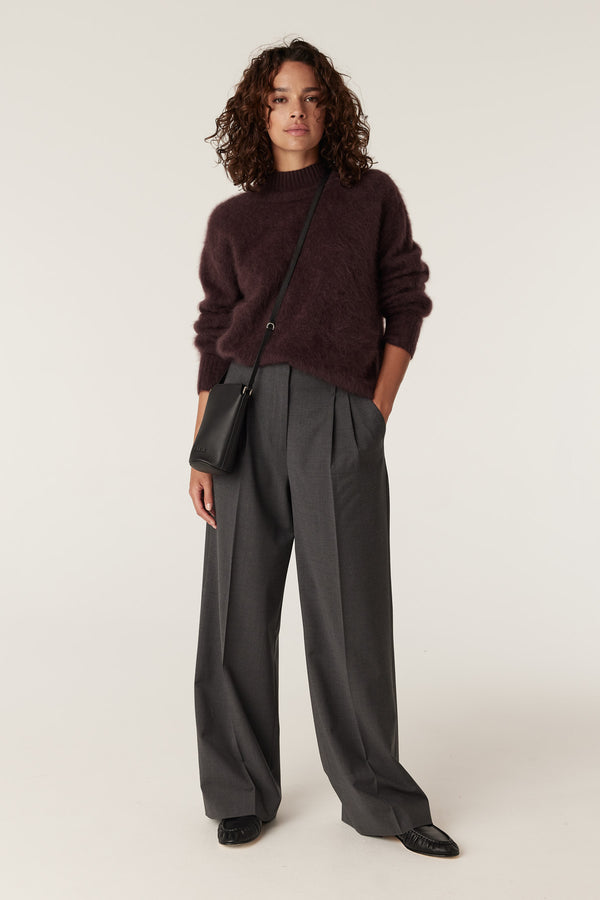 Woman in a brushed Shiraz cashwool turtle neck jumper and grey wide-leg trousers.