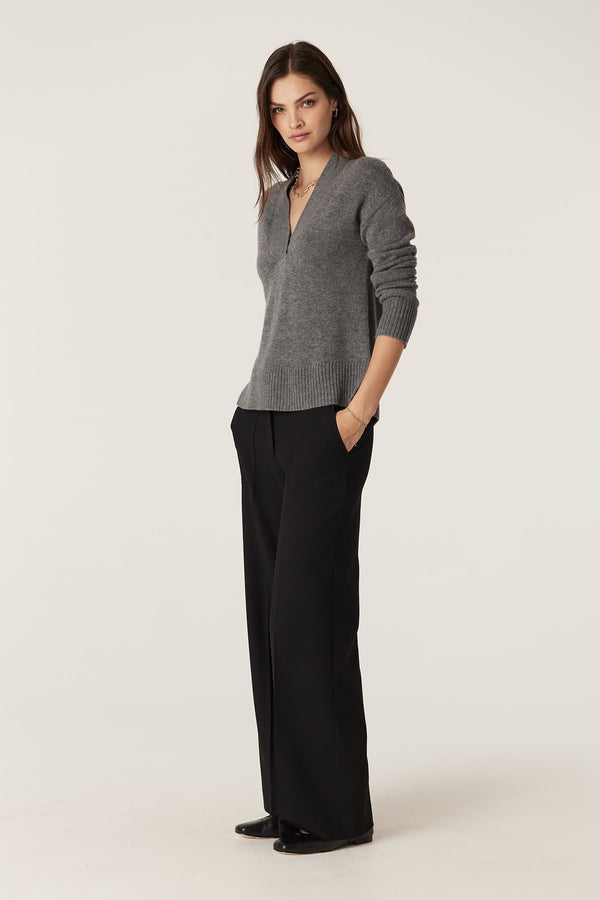 Woman in a mid-grey Cashwool V-neck jumper with rib trims, paired with black trousers.