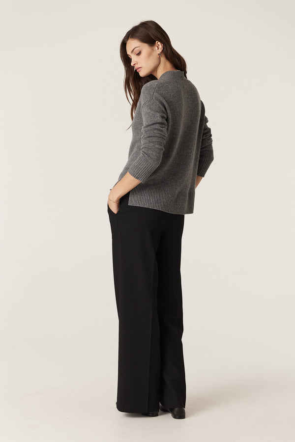 Woman wearing a mid-grey Cashwool V-neck jumper with ribbed trims and black wide-leg trousers.