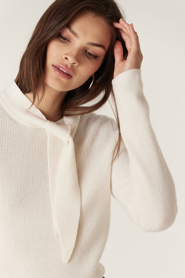 Woman wearing a milk-colored Cashwool tie jumper with a ribbed knit and turtle neckline.
