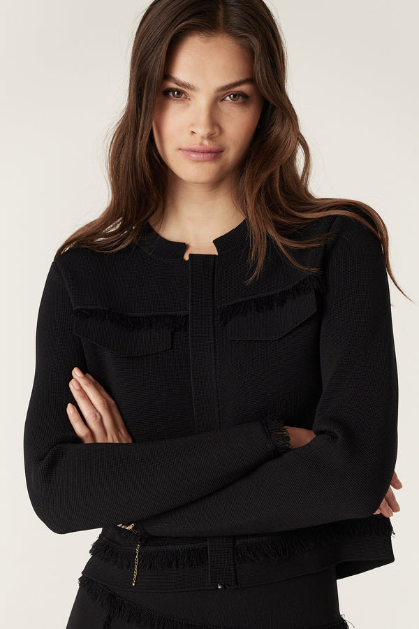 Woman in black crepe fringe jacket with concealed zip, crew neck, and faux bust pockets.