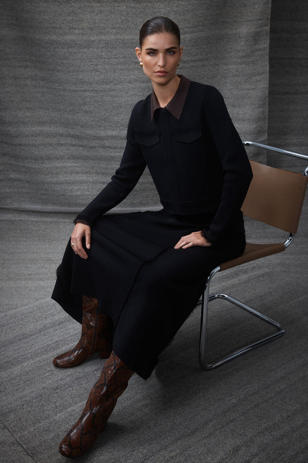 Model wearing a black crepe fringe midi skirt and matching top, paired with brown snakeskin boots.