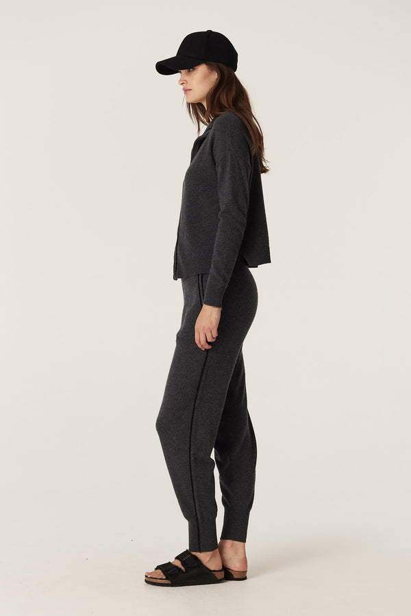 Woman in charcoal Cashwool track zip jumper and matching pants with a black cap.