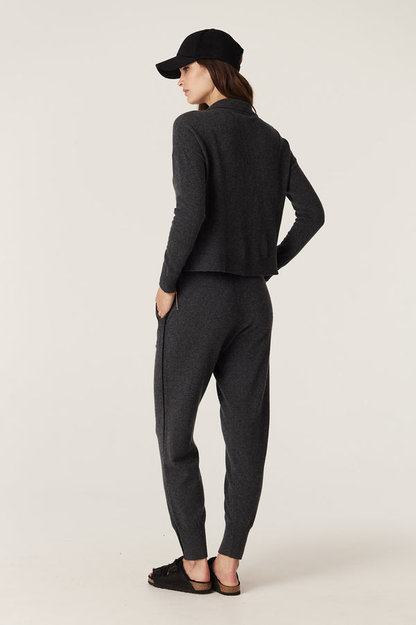 Woman wearing a charcoal Cashwool Track Zip Jumper and matching pants, with a black cap and sandals.