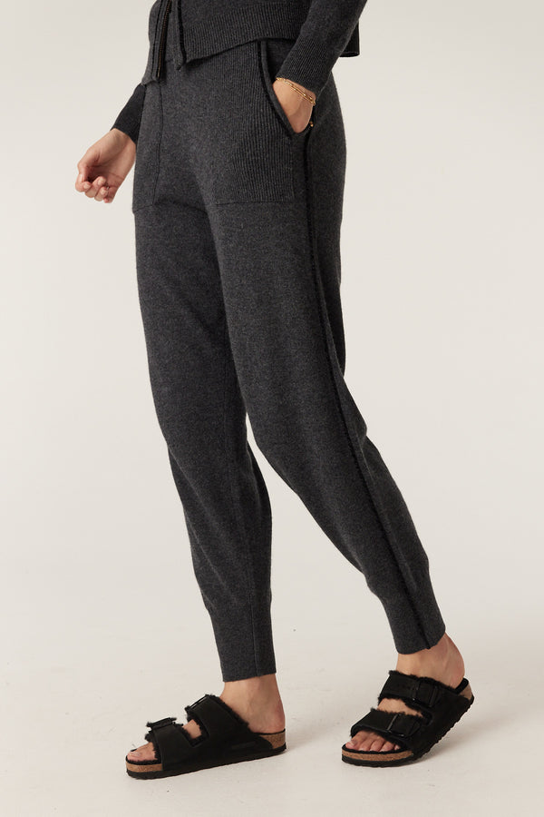 Charcoal Cashwool track pants with ribbed waistband, patch pockets, and chenille cord detail, worn with black sandals.