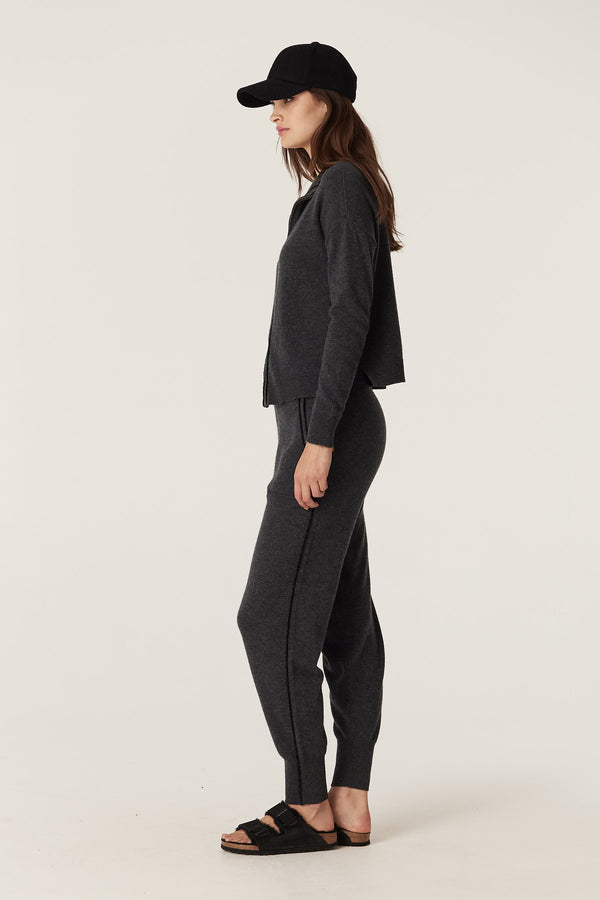 Woman in charcoal Cashwool track pants and matching cardigan, black baseball cap, and sandals.
