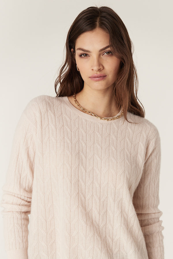 Blush Cashwool cable knit crew neck jumper on a model, showcasing its textured design.