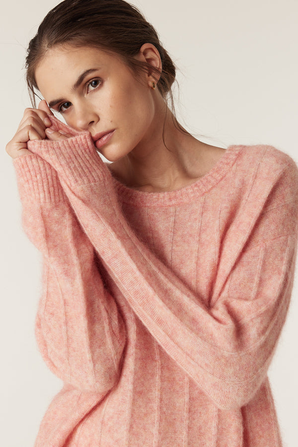 Model wearing a soft melon pink mohair blend crew neck jumper with jersey stripe stitch.