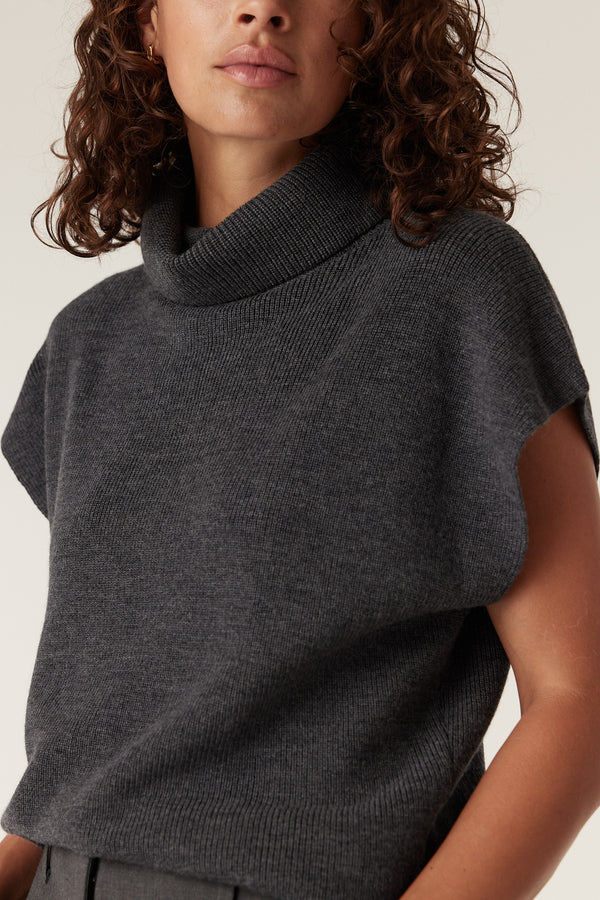 Woman wearing a charcoal Eloise Merino knit top with a relaxed turtleneck and short sleeves.