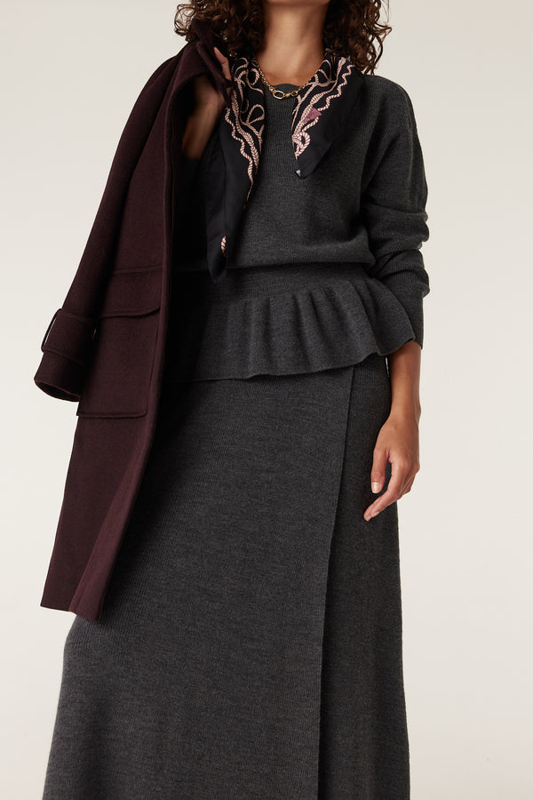 Charcoal Eloise Merino peplum jumper with a matching skirt, styled with a patterned scarf and a burgundy coat.