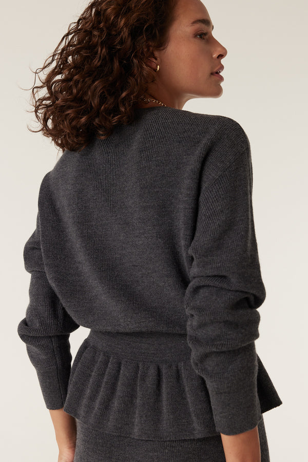 Charcoal merino peplum jumper with ribbed knit and long sleeves on a model.