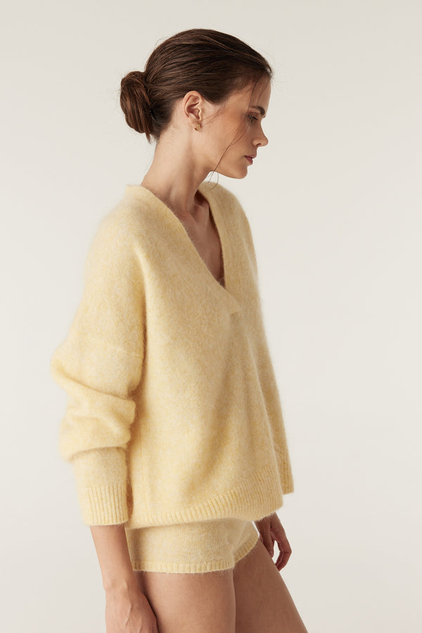 Model wears a soft butter yellow mohair blend V-neck jumper with ribbed cuffs and hem, paired with matching shorts.