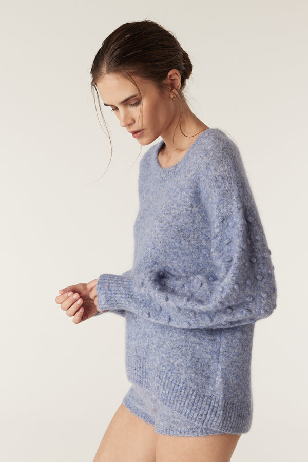 Model wearing a denim blue mohair blend bobble jumper with balloon sleeves and a crew neck.