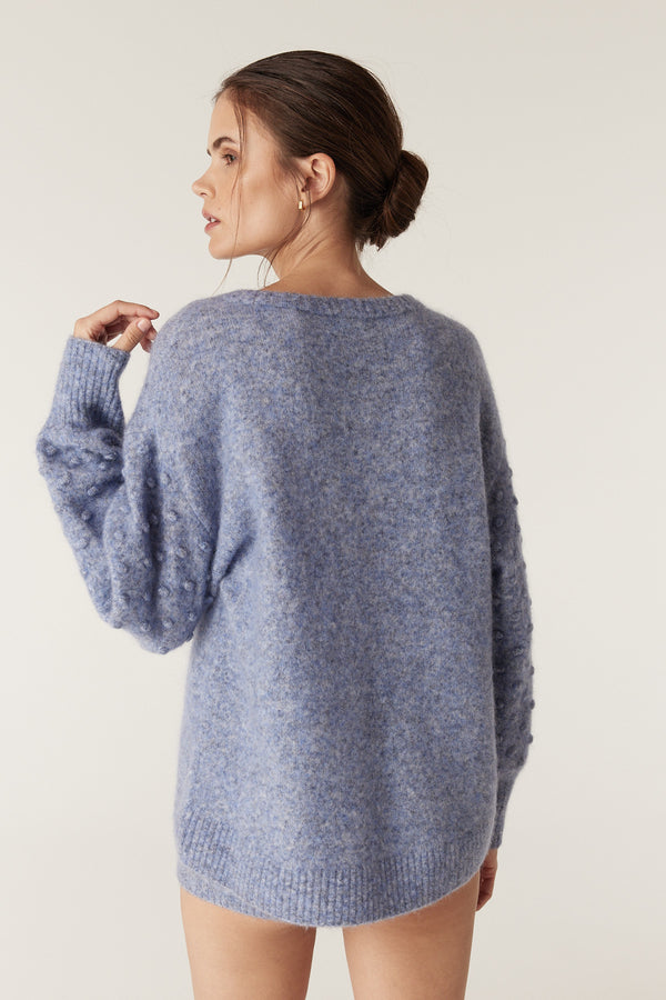 Woman wearing a denim blue mohair blend bobble jumper with balloon sleeves and a crew neckline.
