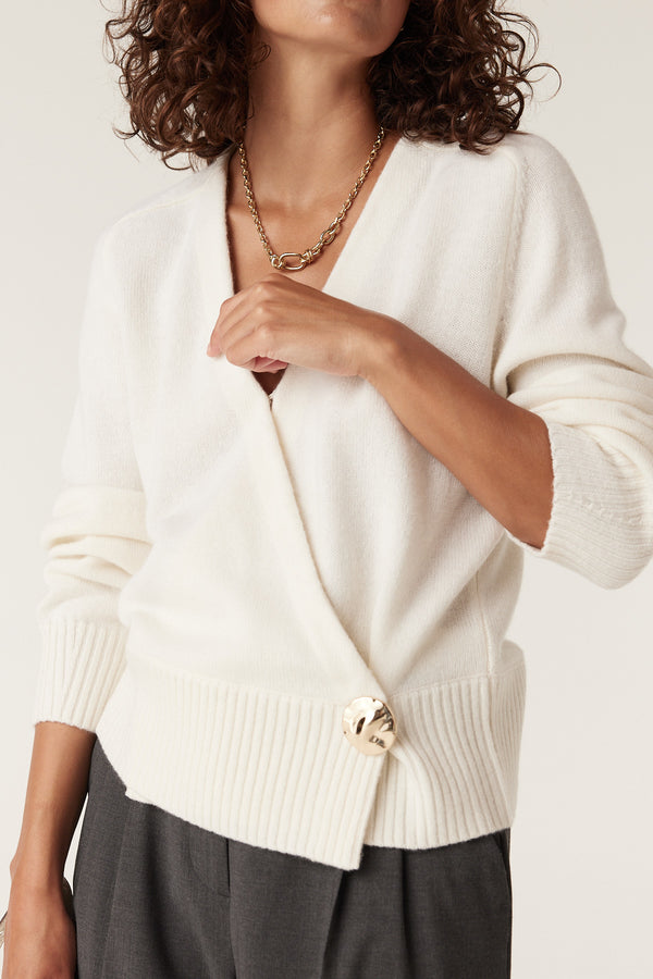 Milk white Cashwool wrap knit jumper with a large gold button closure and ribbed hem.