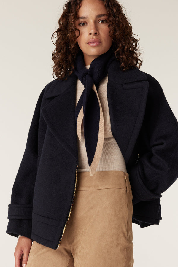 Navy Cashwool neck scarf with beige stripe, tied neatly on a woman wearing a navy jacket.