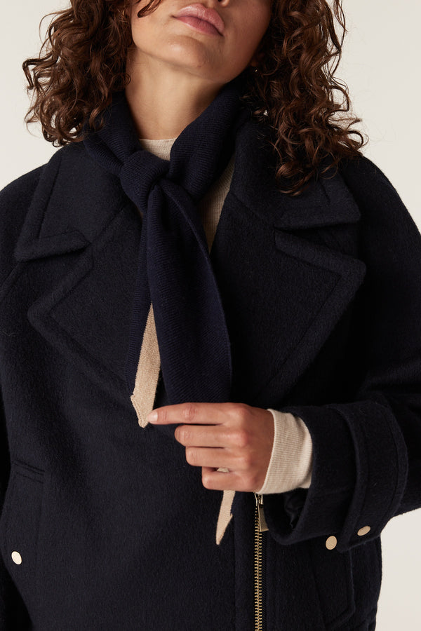 Navy Cashwool neck scarf with beige trim, tied on a woman wearing a navy coat.