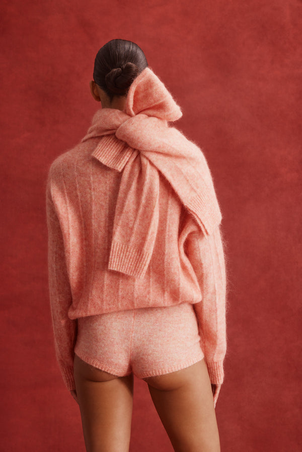 Model from behind wearing a melon mohair blend knit sweater and matching mini shorts with a large bow detail.