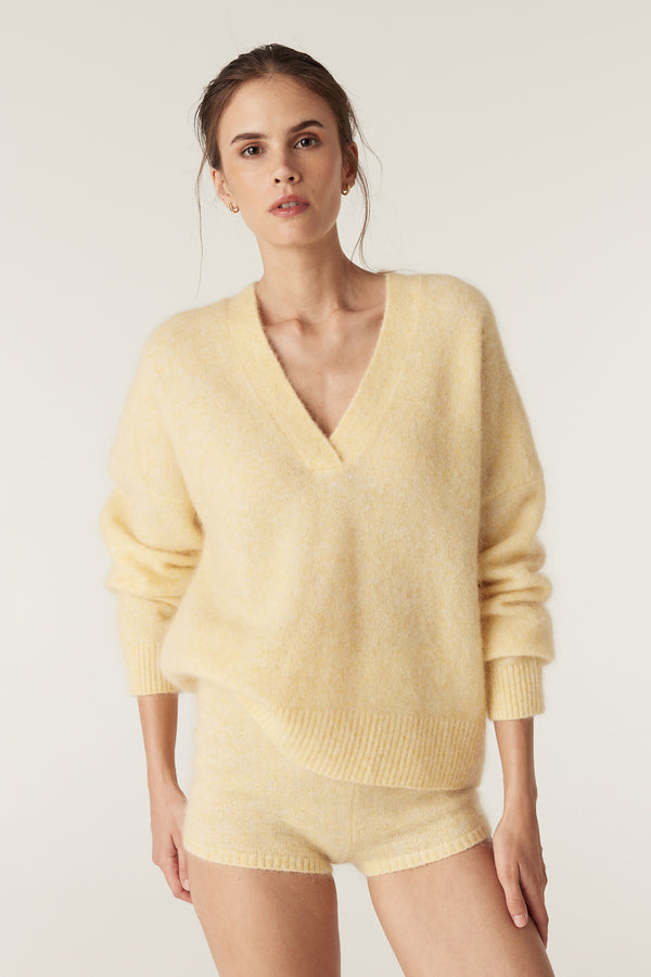 Model wearing a butter yellow mohair blend V-neck jumper and matching knit mini shorts.