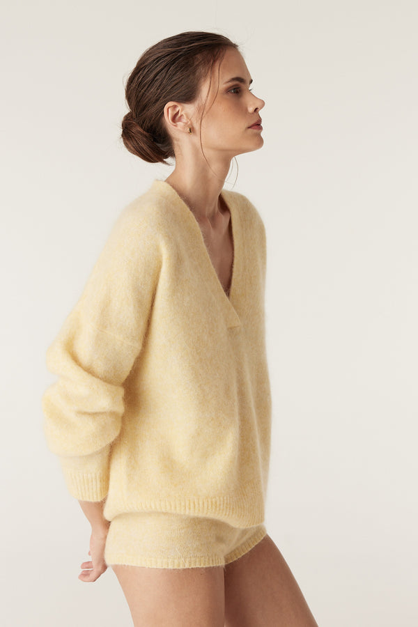 Model wearing a soft, butter yellow mohair blend V-neck jumper and matching mini shorts.