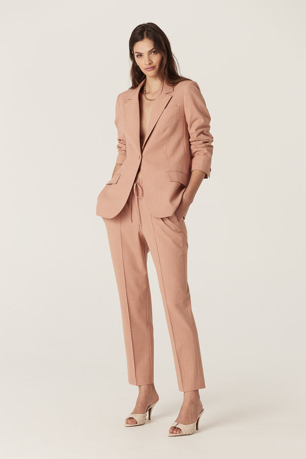 Woman in a clay-colored Owen Pant and matching blazer, featuring a tapered leg and elasticated drawcord waist.