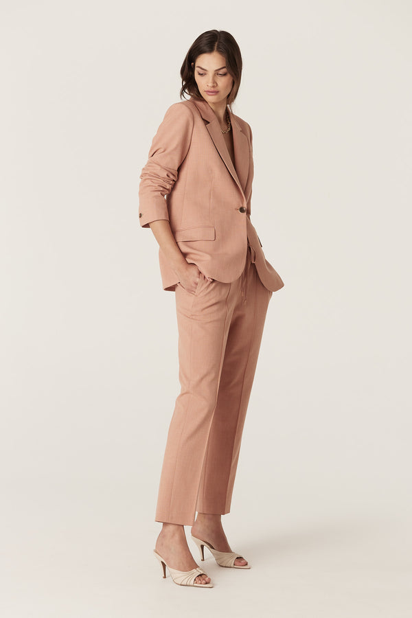 Woman in a clay-colored Owen Pant and matching blazer, featuring a tapered leg and elasticated waist.